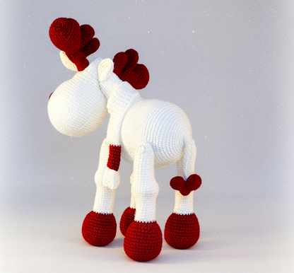 Knitted reindeer toy with red antlers andhooves on a light gray background
