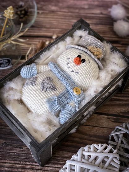 Knitted snowman toy in a decorative box on a wooden surface