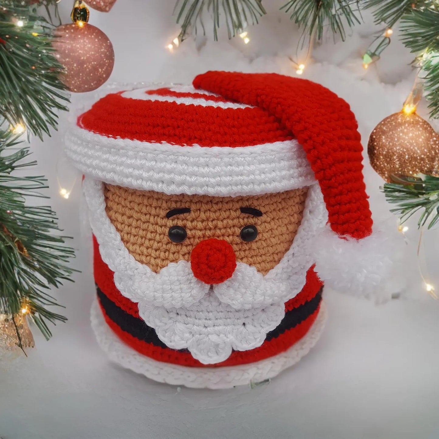 Crocheted Santa Claus decoration with Christmas tree and ornaments in the background