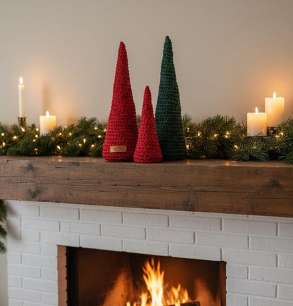 Decorative crochet Christmas trees on a fireplace mantel with candles and garland.