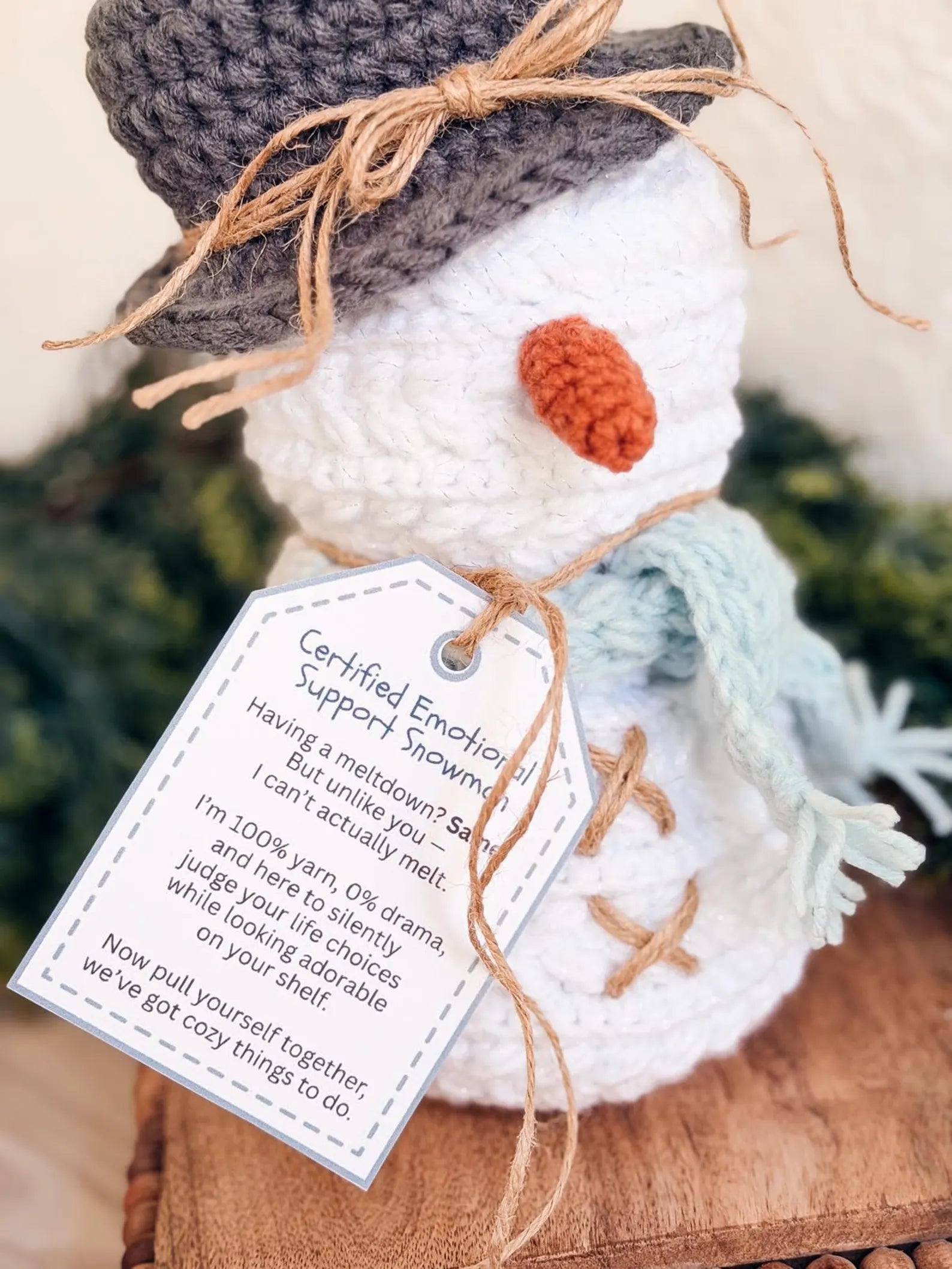 Knitted snowman with a tag on a wooden surface