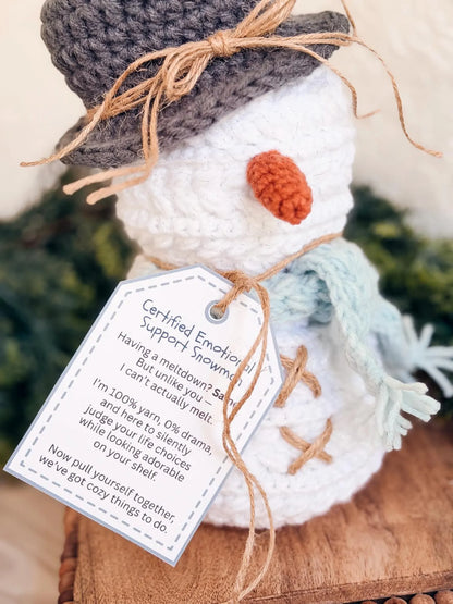 Knitted snowman with a tag on a wooden surface