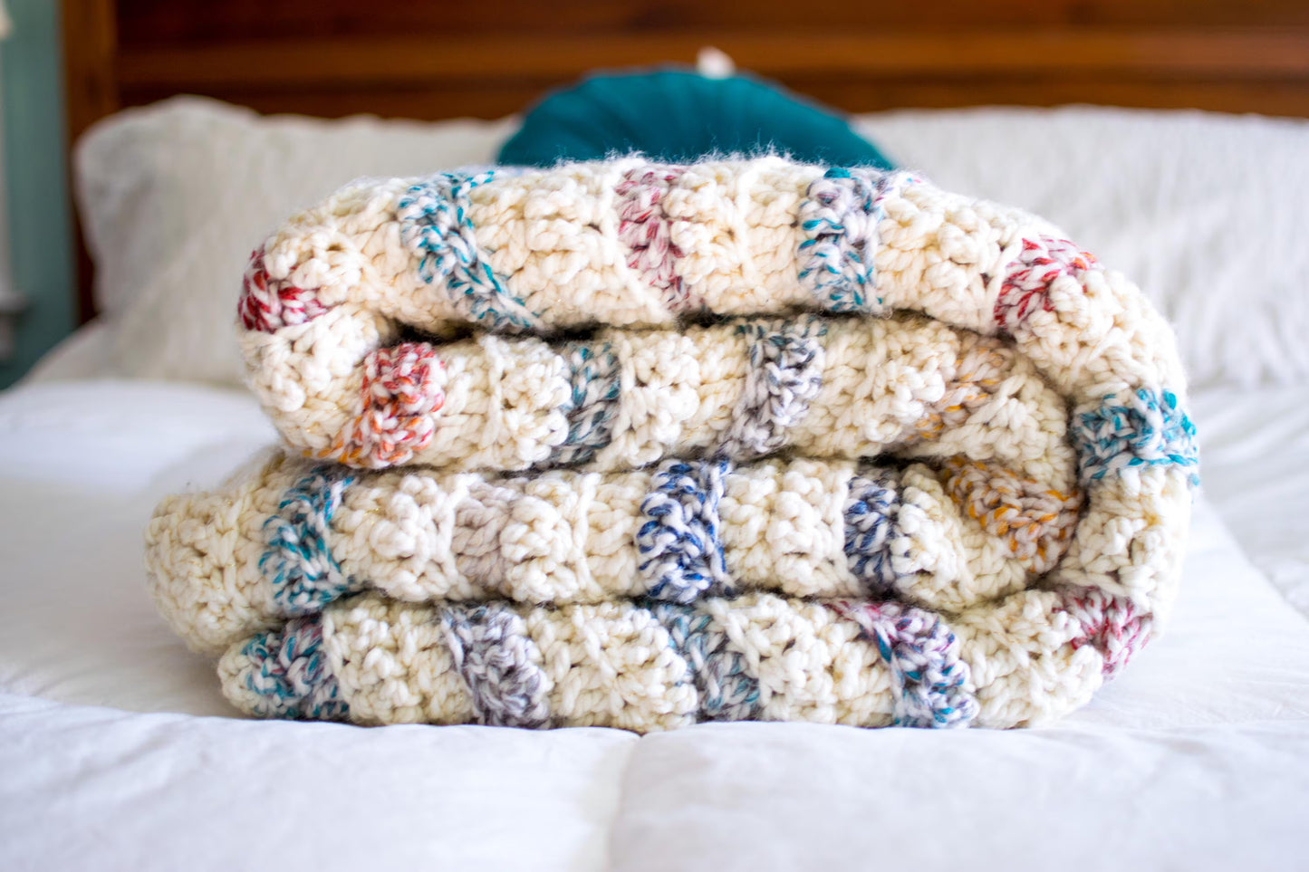 Stack of colorful knitted blankets on a bed